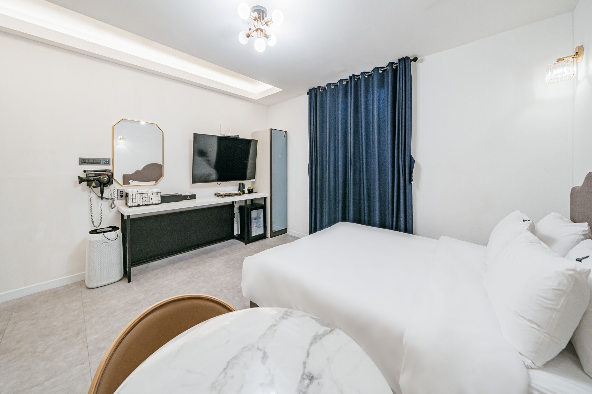 A hotel room with a bed, a desk with a computer, a TV, and a bathroom area.