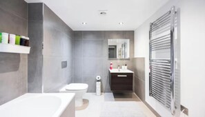 A modern bathroom with a bathtub, toilet, and vanity.