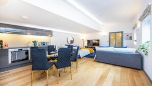 Ein modernes Hotelzimmer mit einer Küchenzeile, einem Essbereich, einem Bett und einem großen Fenster.