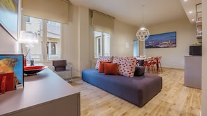 A modern living area with a sofa, dining table, and chairs. There is a painting on the wall and a lamp on the table. - Lucy Florence Charming Modern Apartment  (Florence)