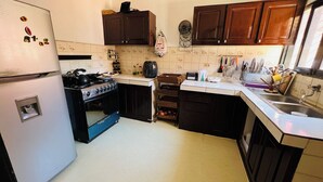 Eine kompakte Küche mit Herd, Backofen und Spüle. Es gibt Holzschränke und eine geflieste Spritzschutzwand.