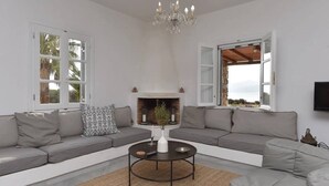 Un salon moderne avec une cheminée, des canapés gris, une table basse ronde et un lustre.