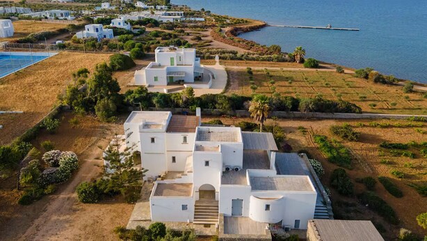 Un village côtier aux bâtiments blancs, offrant une vue dégagée sur la mer et sur une île située au loin.