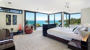 Un dormitorio moderno con una cama grande, zona de estar y vistas al mar.