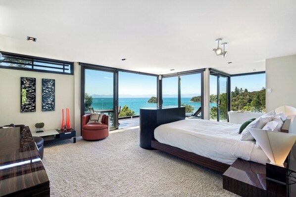 Une chambre moderne dotée d’un grand lit, d’un coin salon et offrant une vue sur la mer.