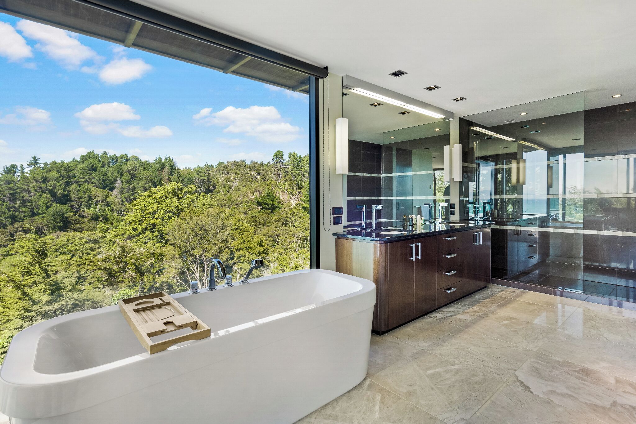 A modern bathroom with a large bathtub, dark wooden cabinets, and a glass shower enclosure.