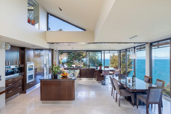 A modern kitchen with a central island, large windows, and a view of the sea. - Exclusive Suite Booking (Kaiteriteri)