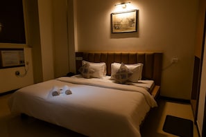 Una cama bien hecha con cabecera, dos almohadas y una toalla enrollada sobre la cama.
