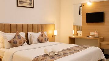 A hotel room with a bed, a bedside table, a TV, and a framed picture on the wall.