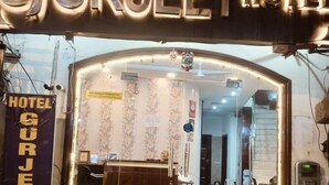 L’entrée de l’hôtel Gurkeet se compose d’un comptoir d’accueil, d’un escalier menant à l’intérieur et d’un panneau indiquant que des chambres climatisées sont disponibles.
