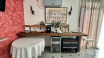 Una cocina con encimera de madera, refrigerador, pileta y una mesa de comedor con mantel blanco.
