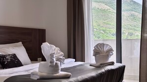 A hotel room with a bed, a large window, and a view of a mountainous landscape. - West Gate (Sutomore)