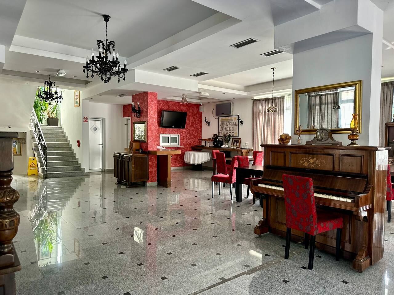 Un vestíbulo espacioso con un piano de cola, una escalera y una pared de acento roja.