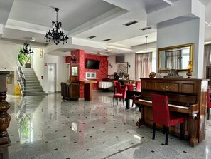 Un vestíbulo espacioso con un piano de cola, una escalera y una pared de acento roja.