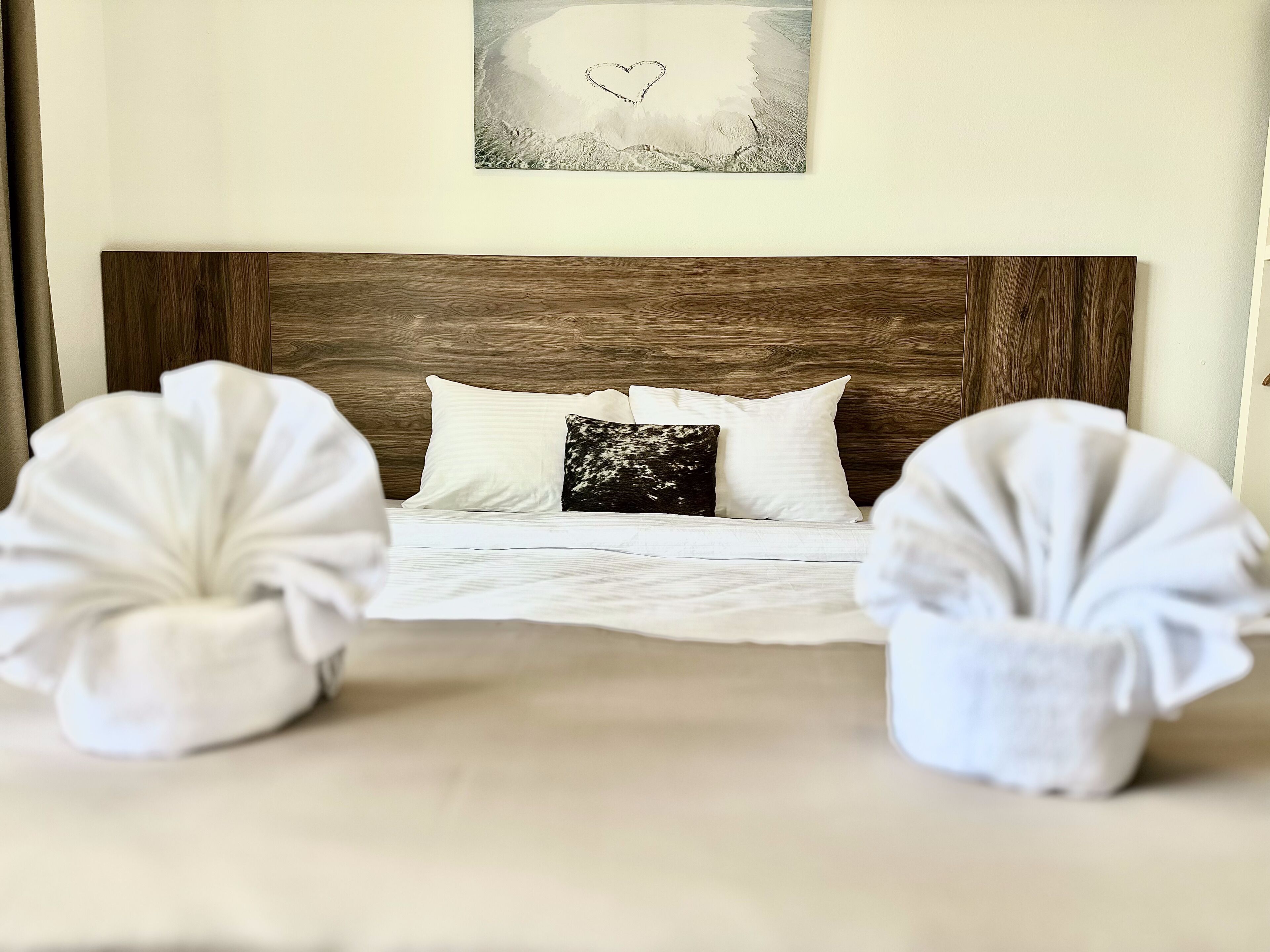 Una cama con cabecera de madera, ropa de cama blanca y dos almohadas blancas.