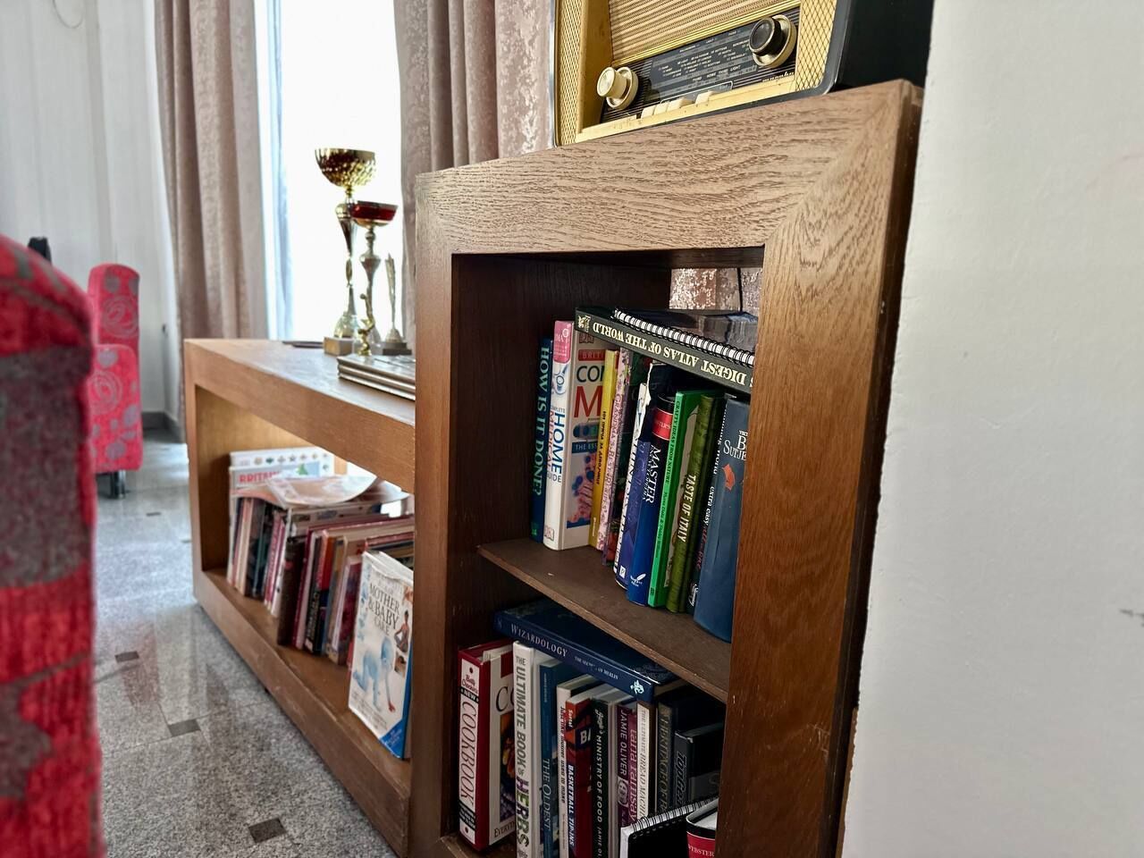 Una estantería con varios libros y una radio.