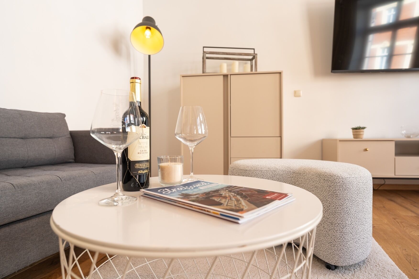 A modern living room with a round white table, a sofa, a cabinet, and a lamp.