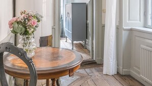 Een eethoek met een ronde houten tafel, een bloemenvaas en een kroonluchter.