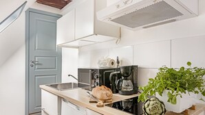 Una cocina moderna con horno empotrado, cafetera y una planta en maceta.