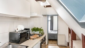 Una cocina compacta con horno integrado, microondas y encimera de madera.
