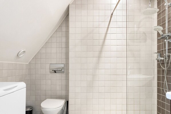 Un baño con ducha, inodoro y barra para toallas.