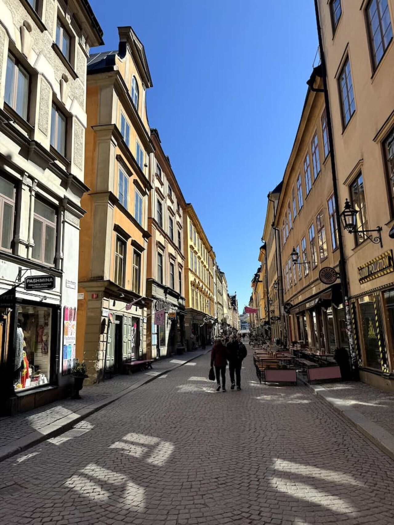 Eine Kopfsteinpflasterstraße gesäumt von historischen Gebäuden, Geschäften und Außenbereich-Sitzgelegenheiten.