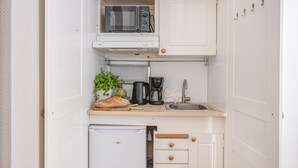 A compact kitchenette with a microwave, coffee maker, and a small refrigerator. - Unik lägenhet i gamla stan (Södermalm)