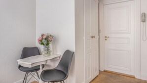 A small room with a white door, a white table with two chairs, and a vase with flowers. - Unik lägenhet i gamla stan (Södermalm)