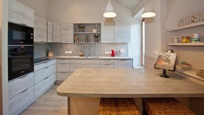 Een moderne keuken met een groot eiland, inbouwapparatuur en open planken.