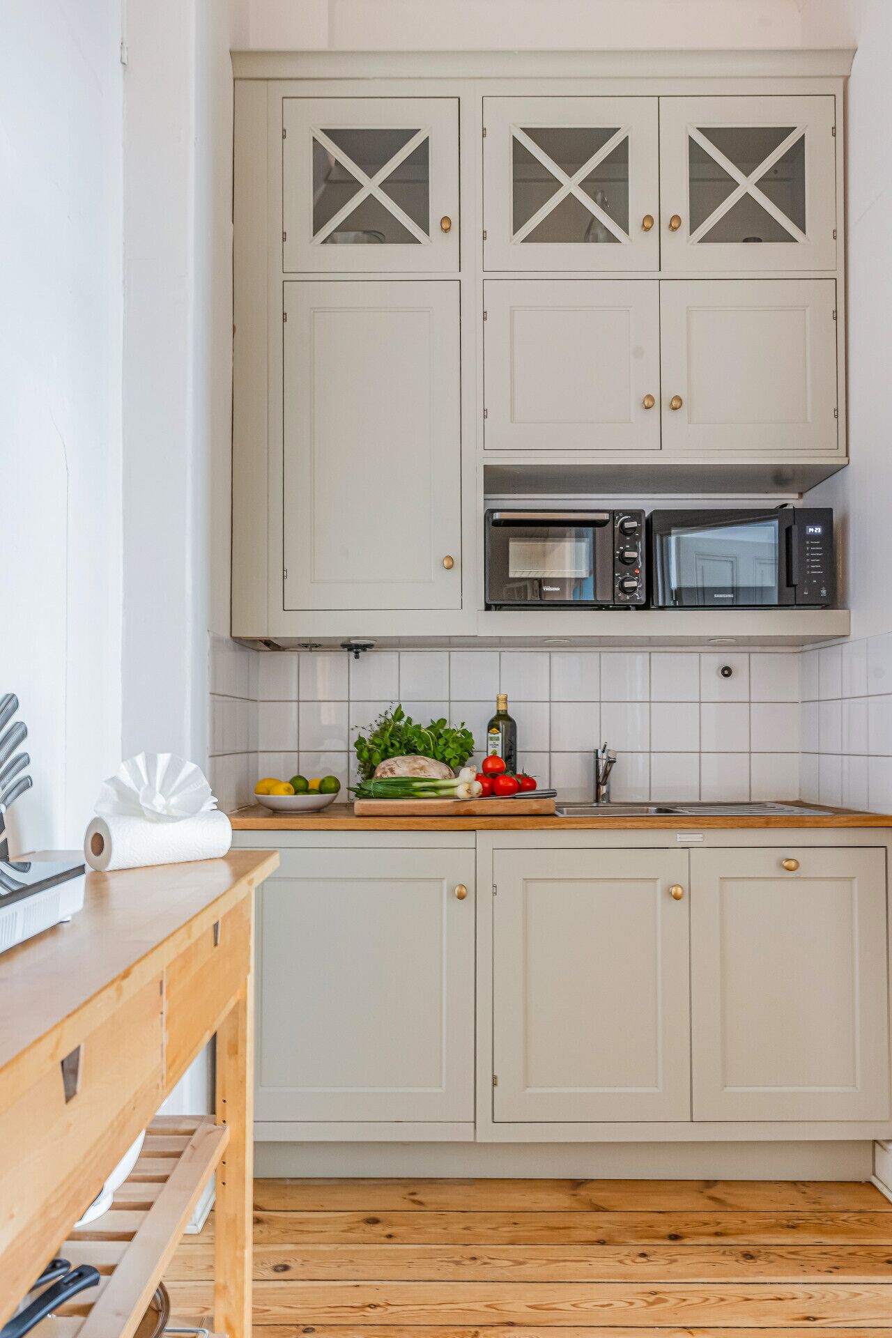 Une cuisine avec des meubles blancs, un four à micro-ondes et un plan de travail en bois.