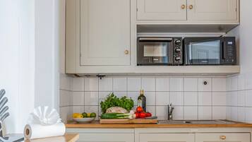 Une cuisine avec des meubles blancs, un four à micro-ondes et un plan de travail en bois.