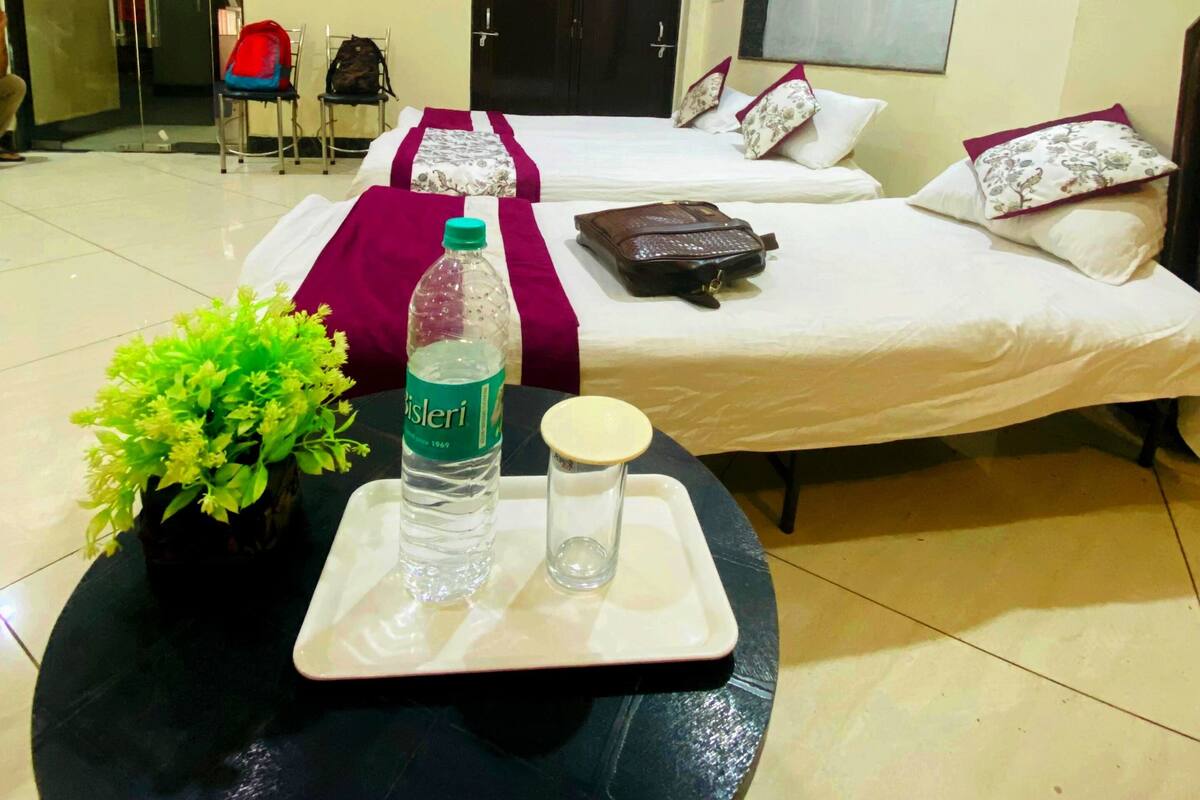 Ein Hotelzimmer mit Bett, Deckenventilator, Fenster und kleinem Tisch mit Flasche und Gläsern.