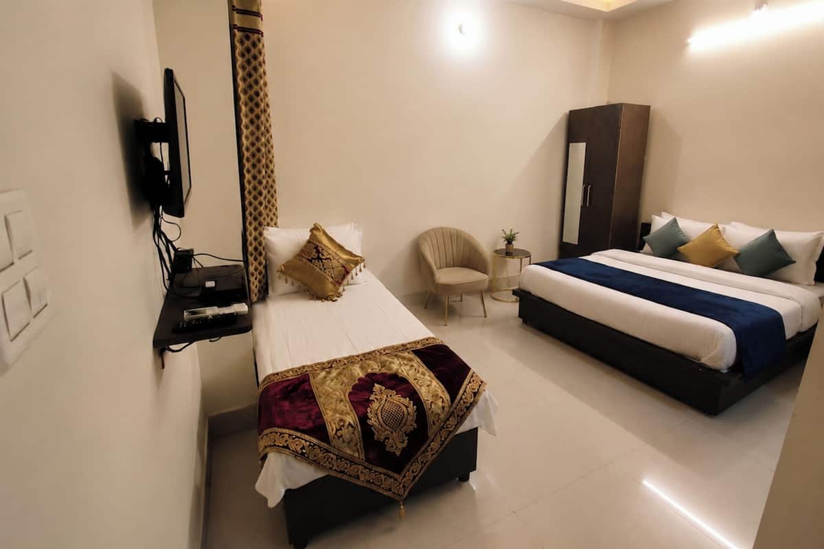 A hotel room with a bed, a chair, a wardrobe, and a television.