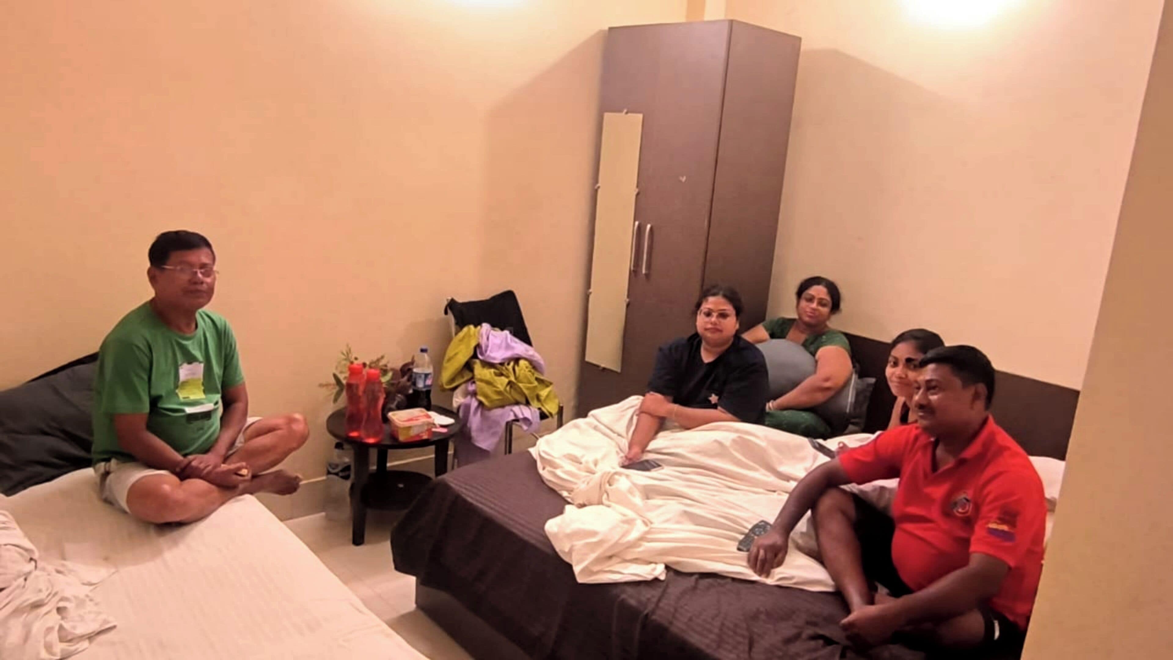 A room with a bed, a small table with items, a wardrobe, and a sofa.