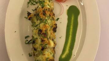 A plate with a baked dish, a green sauce, and a side salad.