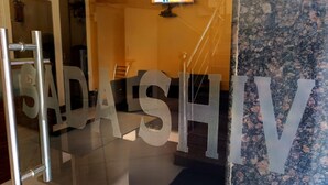 Une porte en verre sur laquelle est inscrit en grandes lettres le nom « GADASHIV », un extincteur accroché au mur et un écran de télévision en arrière-plan.