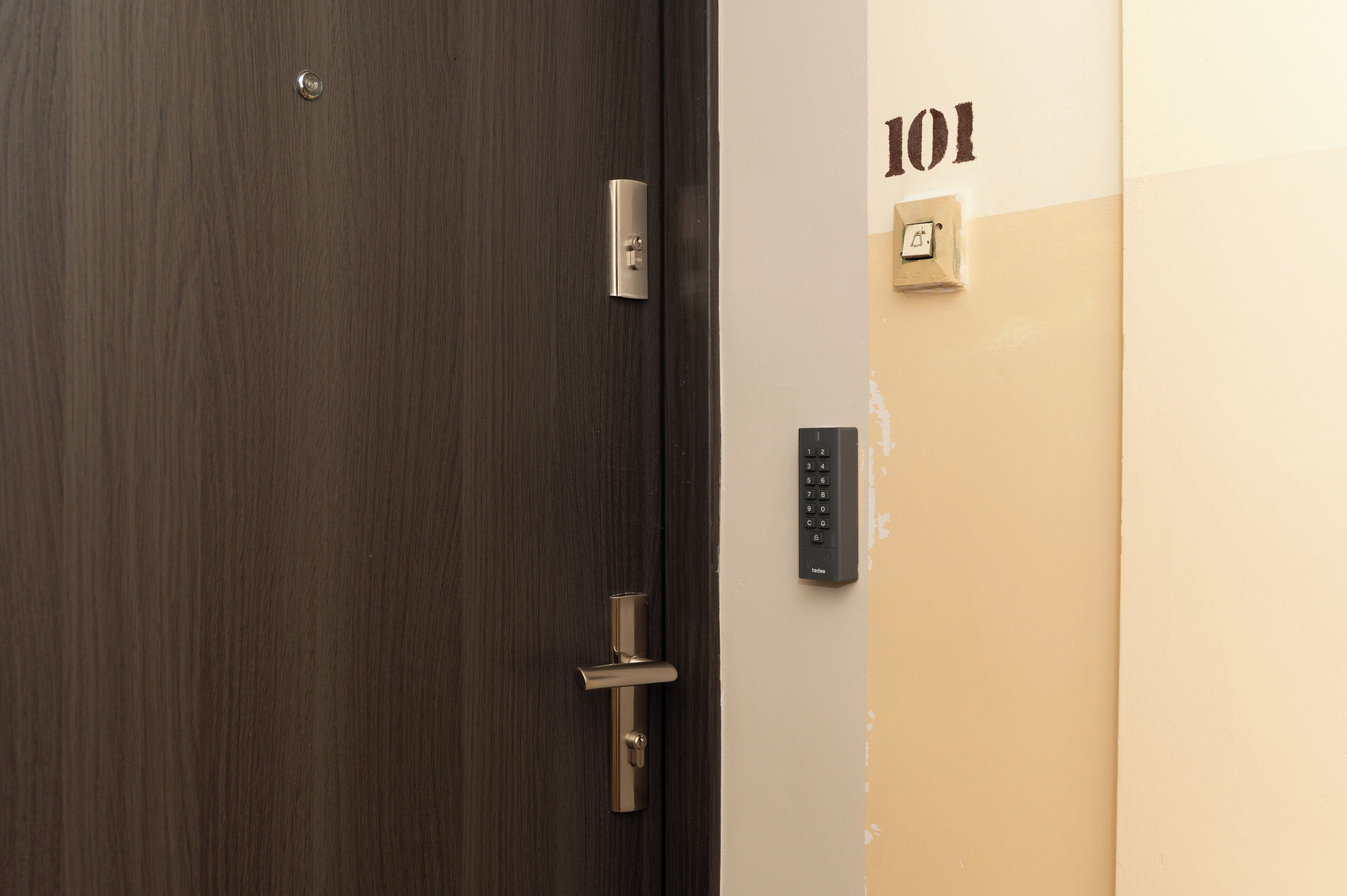 A door with a modern lock and a keypad on the wall beside it.
