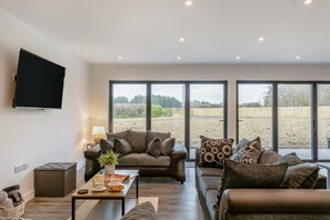 Un salon moderne avec un ensemble de canapés, une table basse et un téléviseur fixé au mur.