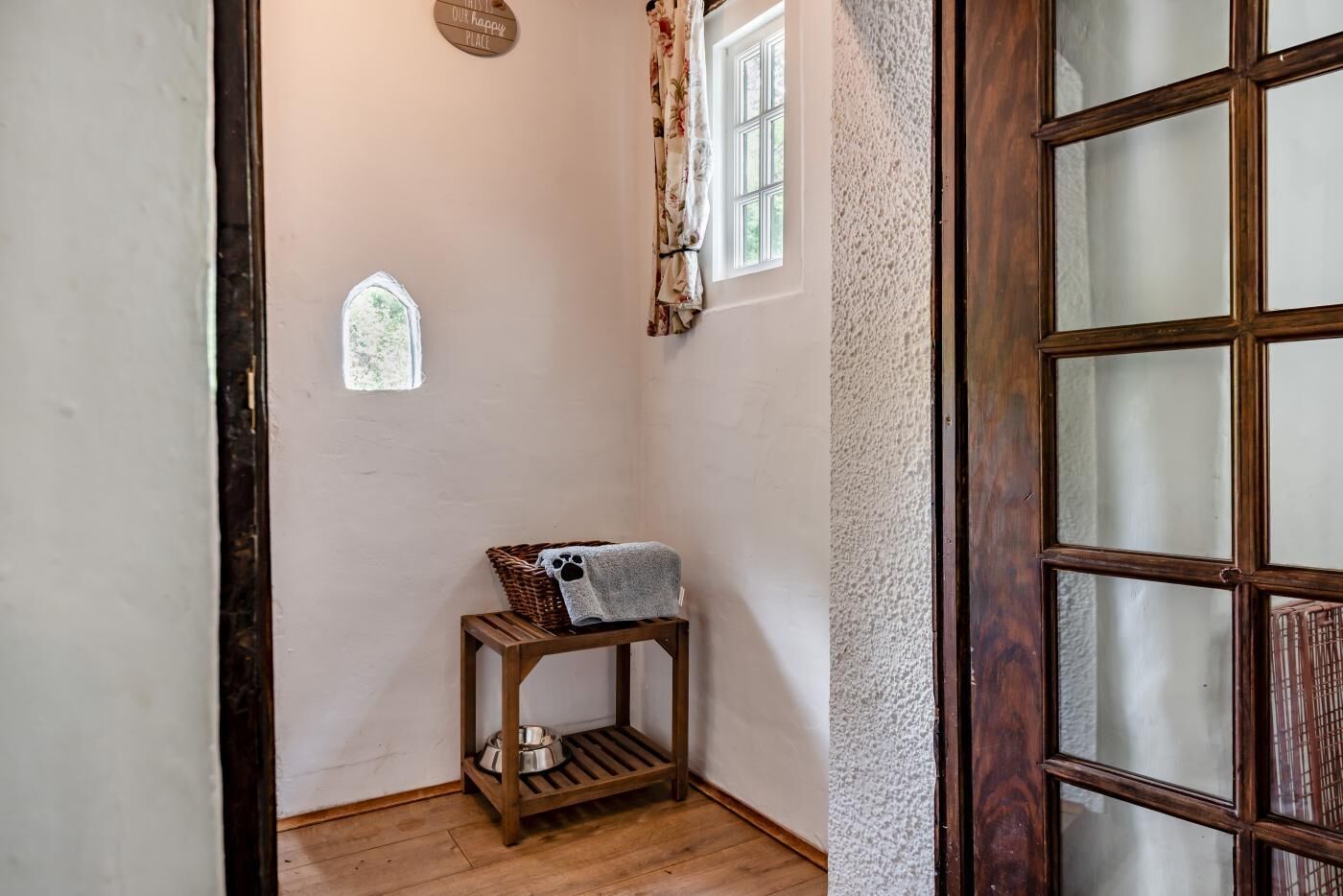 A corner of a room with a wooden bench, a small window, and a door with frosted glass panels.