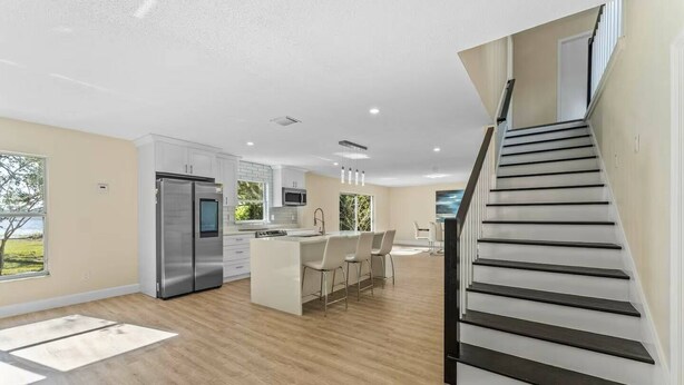 Een moderne keuken met een centraal eiland, roestvrijstalen apparatuur en een eethoek met stoelen.