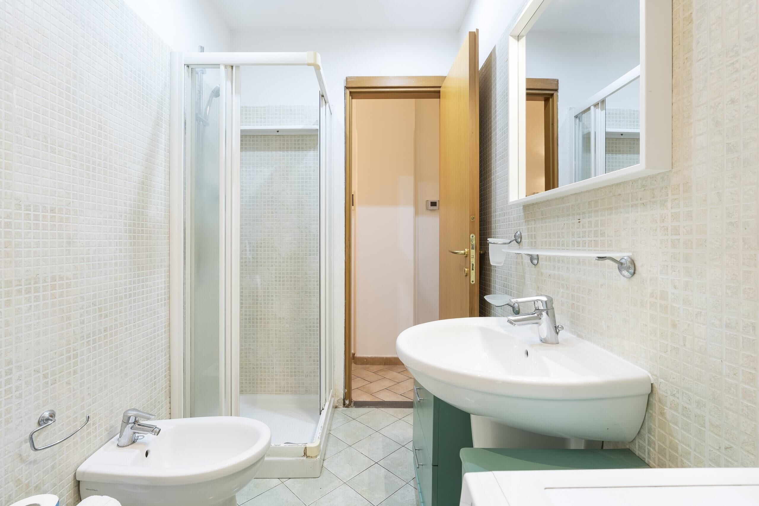 A bathroom with two sinks, a shower, and a toilet.