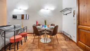 Un comedor con una mesa redonda, cuatro sillas, un sofá y una puerta de madera.