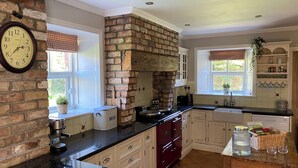 Une cuisine avec un mur en briques, des armoires en bois, un plan de travail noir et une horloge au mur.