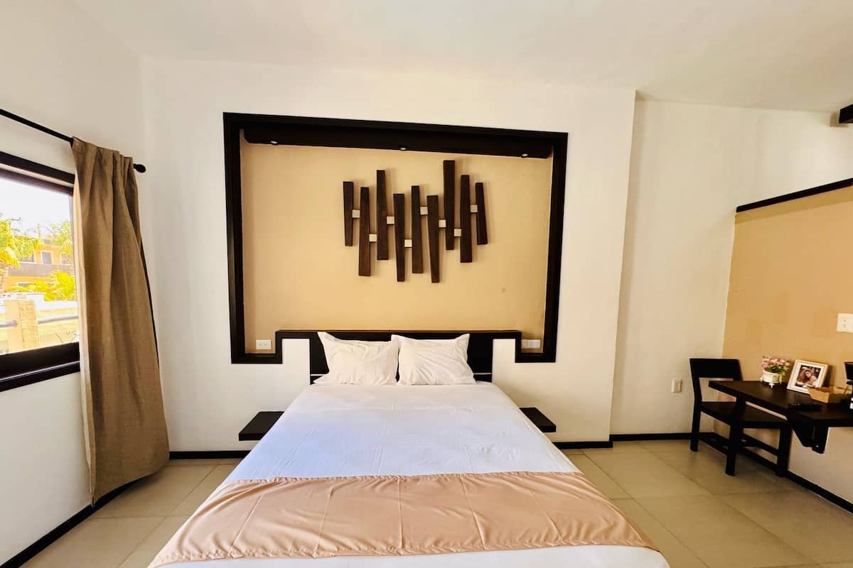 Une chambre d’hôtel avec un lit, un bureau et une œuvre d’art accrochée au mur.