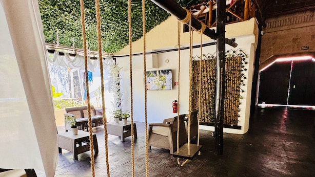 Un espace de détente intérieur accueillant, avec des meubles en osier, une balançoire et un mur en bambou.
