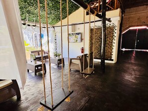 A cozy indoor seating area with wicker furniture, a swing, and a bamboo wall. - Original Maya Bric (Playa del Carmen)