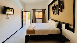 Une chambre d’hôtel moderne, équipée d’un lit, d’un téléviseur fixé au mur et d’une fenêtre avec des rideaux.