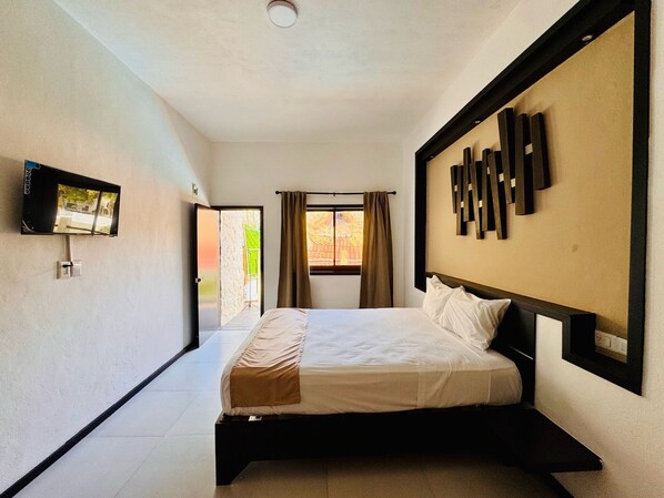 A modern hotel room with a bed, a TV mounted on the wall, and a window with curtains. - Original Maya Bric (Playa del Carmen)
