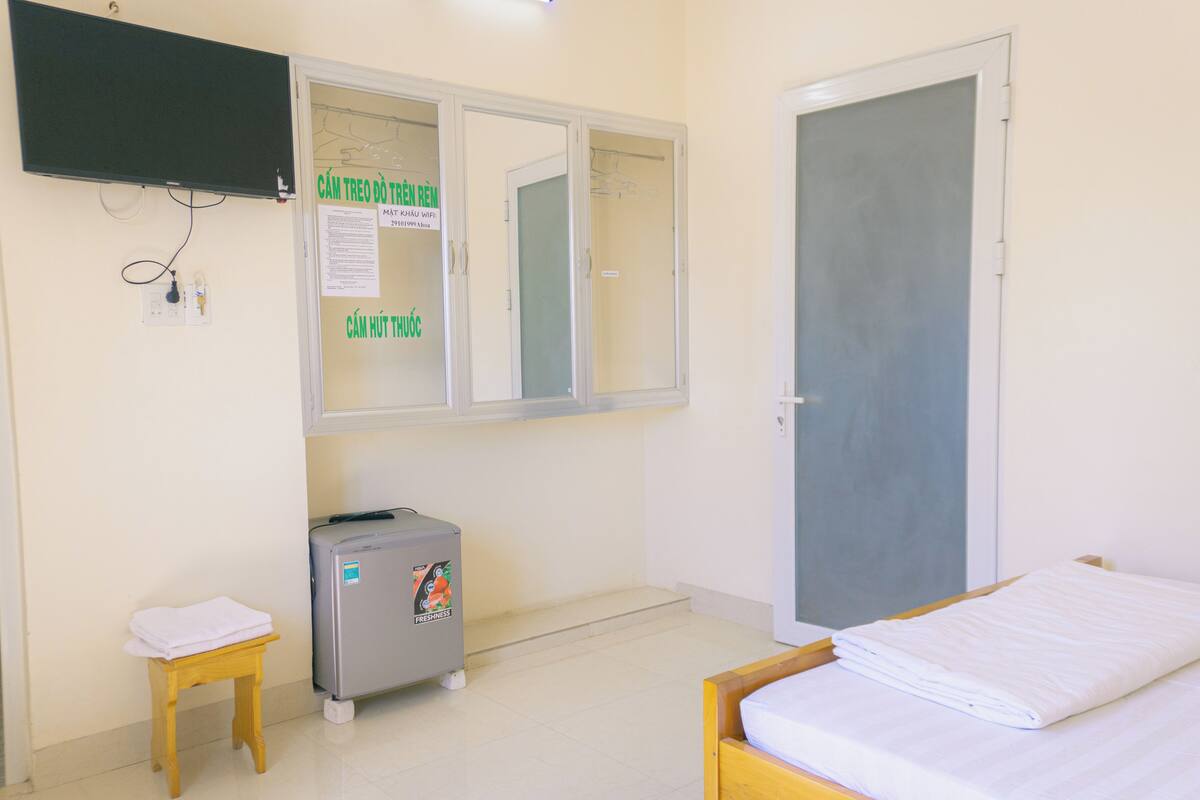 A room with a bed, a small table, a cabinet, and a door.