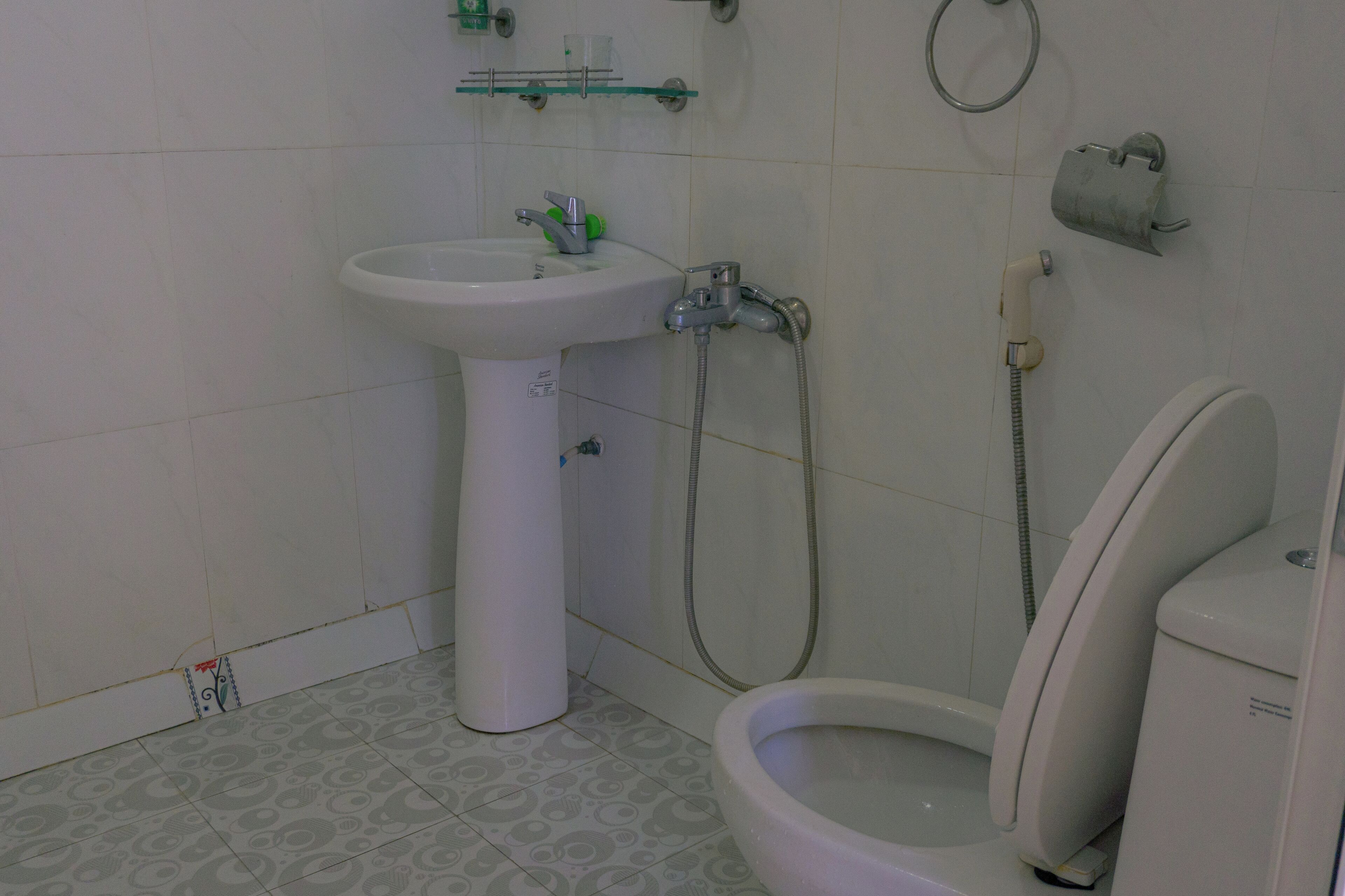 A bathroom with a pedestal sink, a toilet, and a shower.